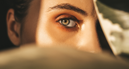 A close-up view of the back of a person's head and an ear, with a soft, warm-toned background.